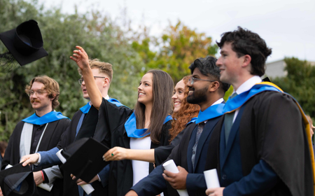 UCD graduates celebrating throwing caps in the air.